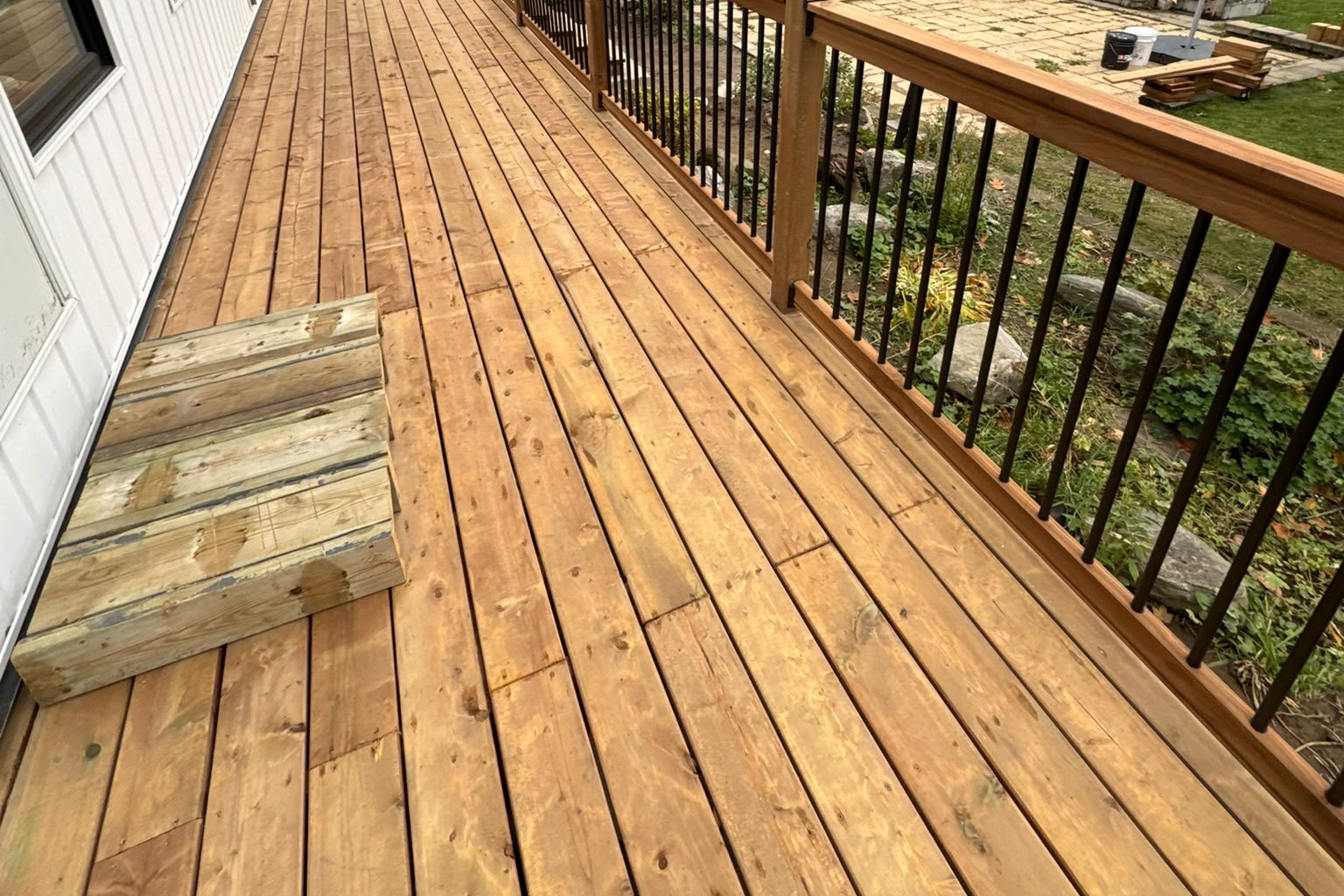 Finished backyard deck with stained cedar decking and black metal railing