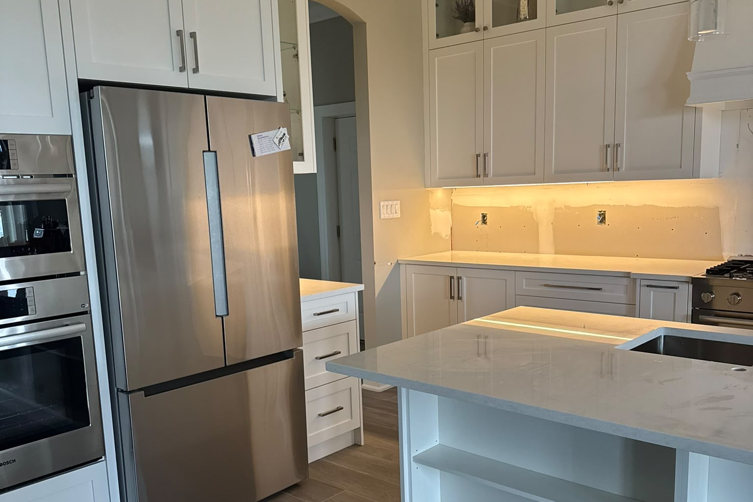 Finished kitchen with white shaker cabinets, quartz island and stainless appliances