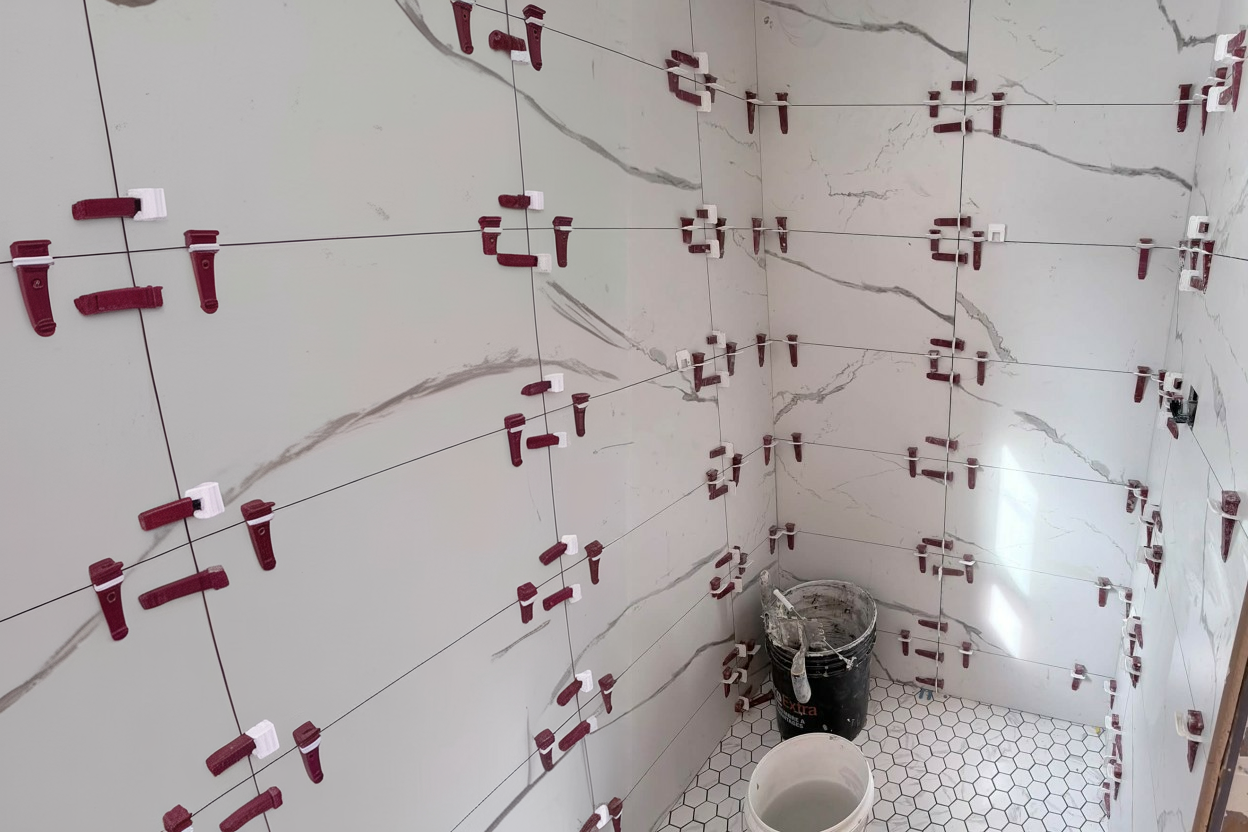 Shower wall mid-tile-installation with porcelain slab tile and alignment clips