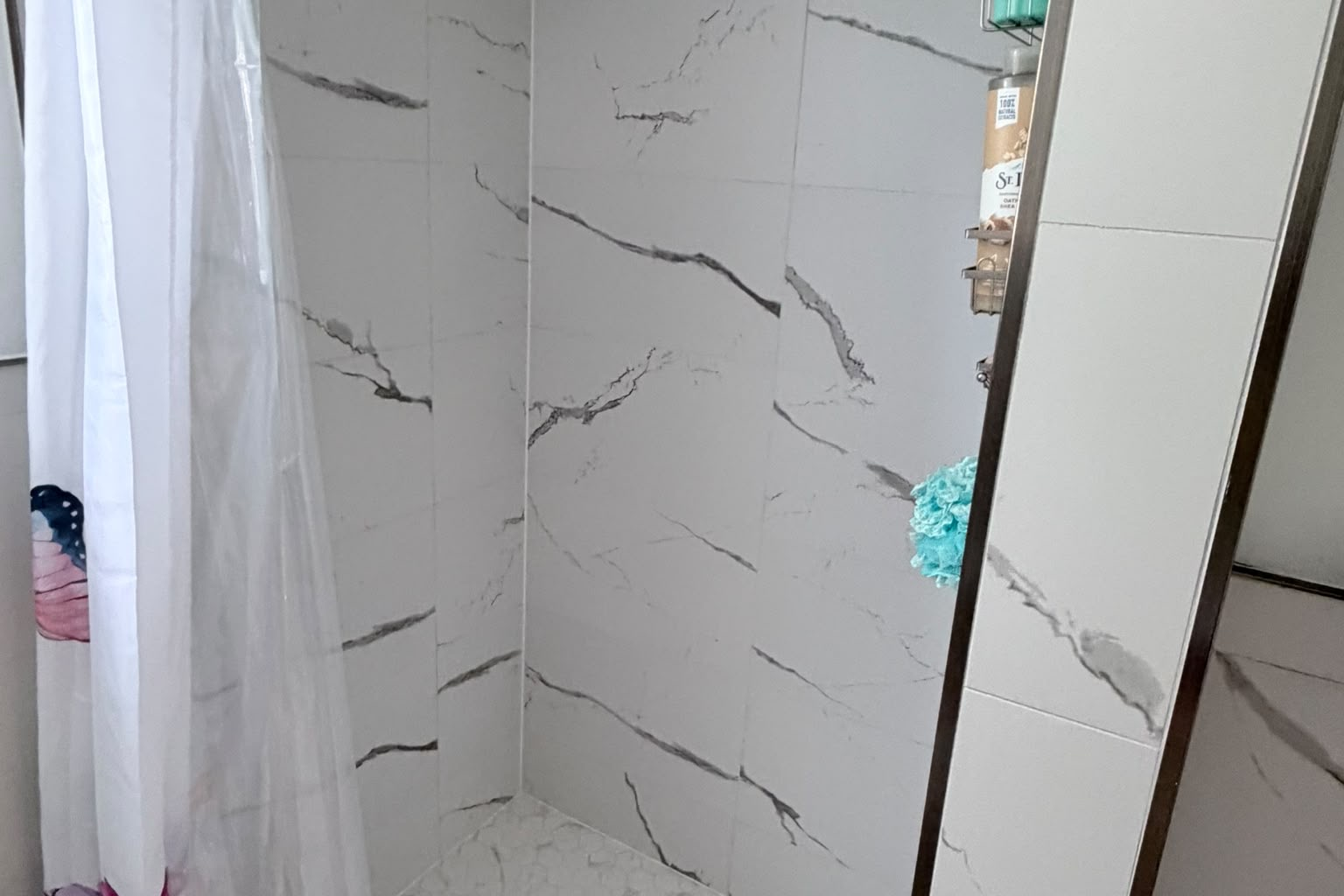 Finished shower with marble-look porcelain tile floor to ceiling
